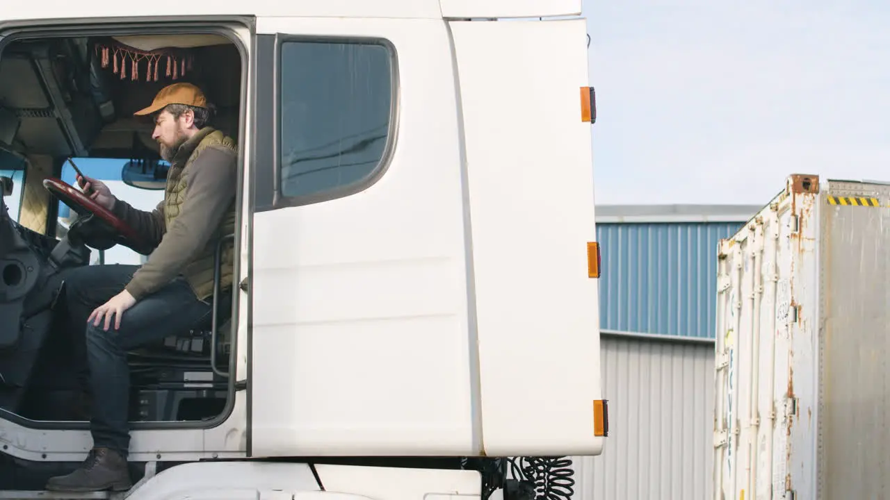 Arbeiter Mit Weste Und Kappe Der Eine Lkw-flotte In Einem Logistikpark Organisiert Während Er In Einem Lkw Telefoniert