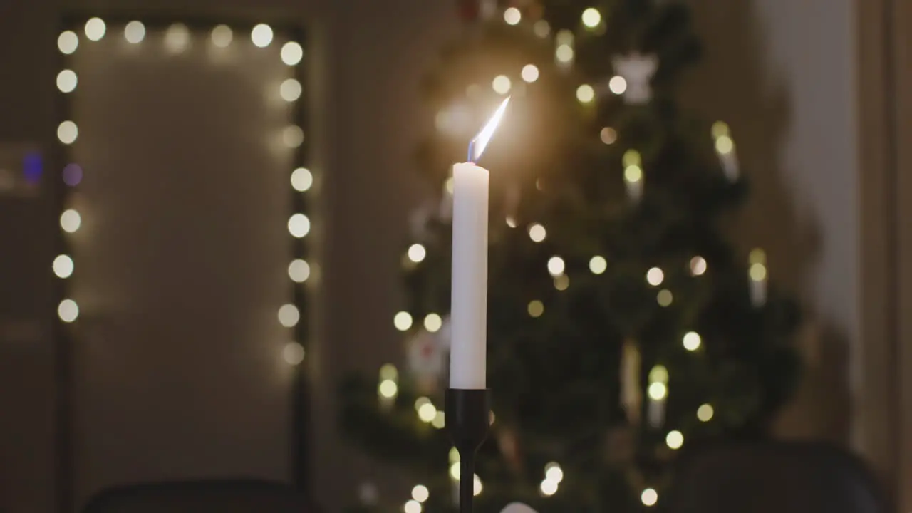 Die Kamera Fokussiert Auf Eine Brennende Kerze Im Hintergrund Steht Ein Weihnachtsbaum Mit Verschwommenen Lichtern 1