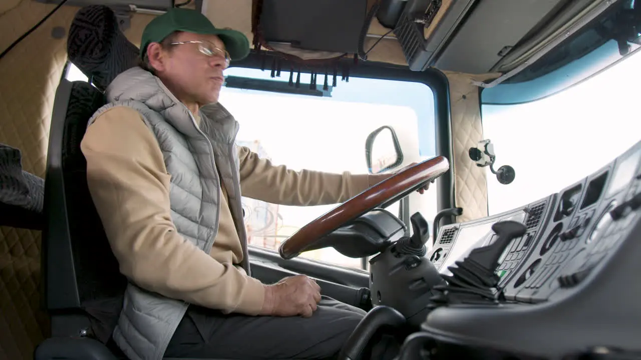 Seitenansicht Eines älteren Arbeiters Mit Mütze Und Weste Der Einen LKW In Einem Logistikpark Fährt 6