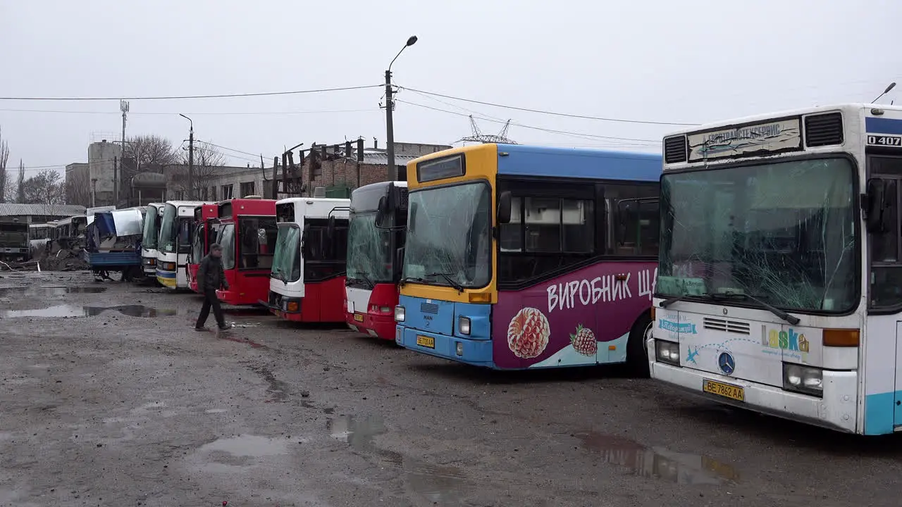 A worker walks past buses lined up at a depot have shattered windscreens damage caused by a Russian S-300 missile striking the civilian infrastructure site in the early hours of the morning