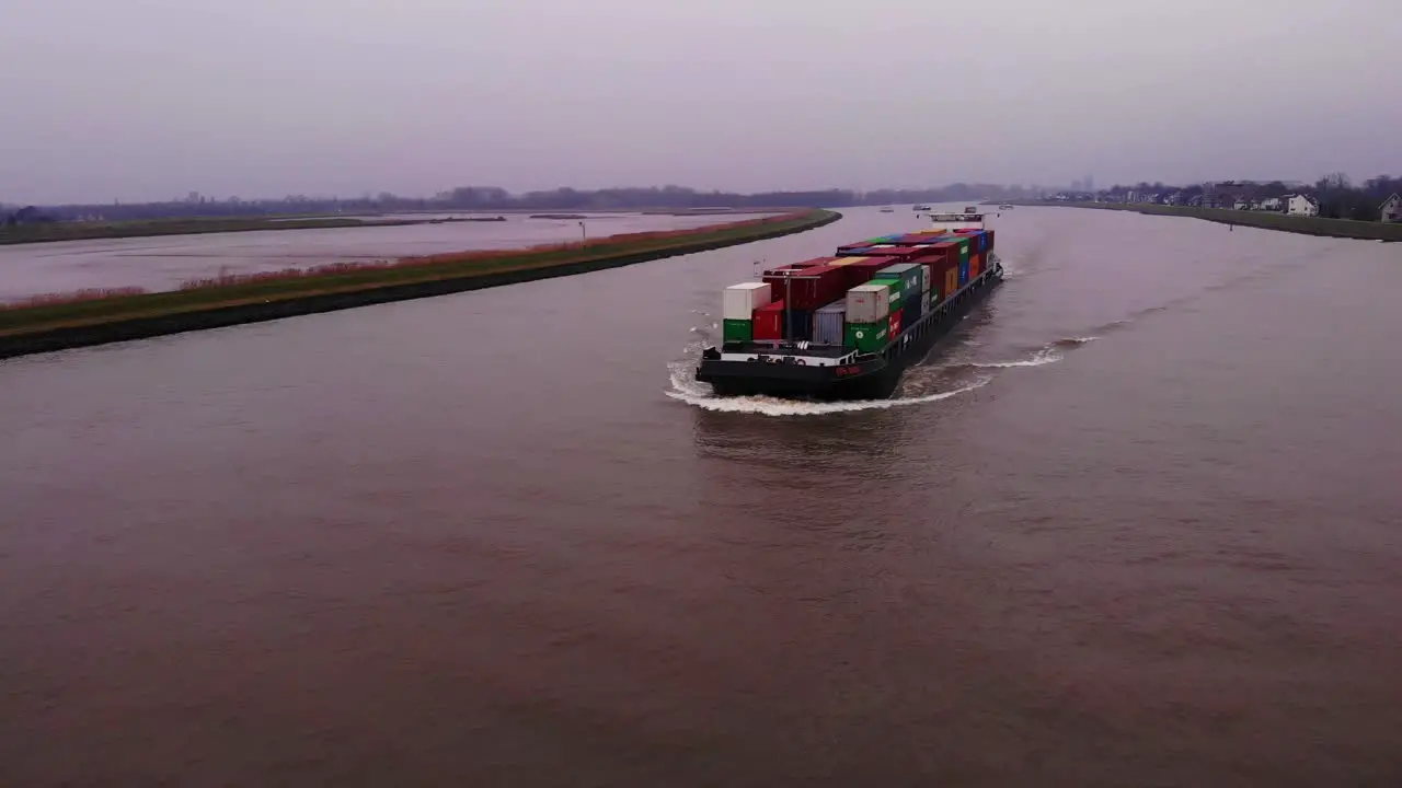 Aerial Over River Noord With View Of FPS Rijn Ship Carrying Containers Approaching On Cloudy Day