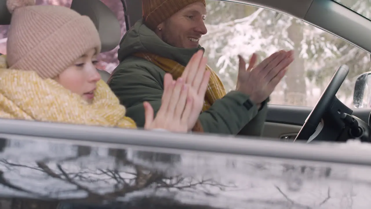 Side View Of A Girl And Her Father Sitting In The Car Warming Their Hands With Their Mouths And Putting Them In The Air Conditioner