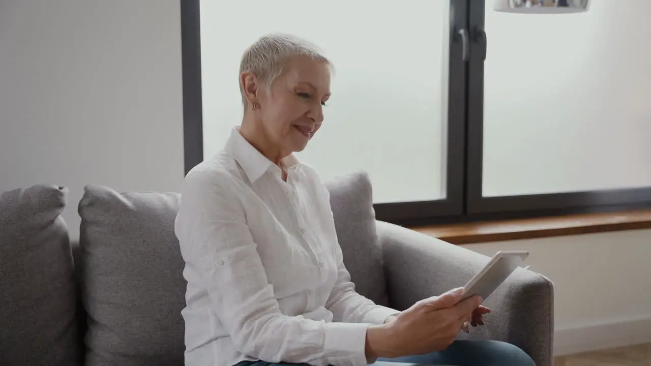 Seniorin Mit Kurzen Blonden Haaren Die Mit Einem Tablet Auf Dem Sofa Sitzt