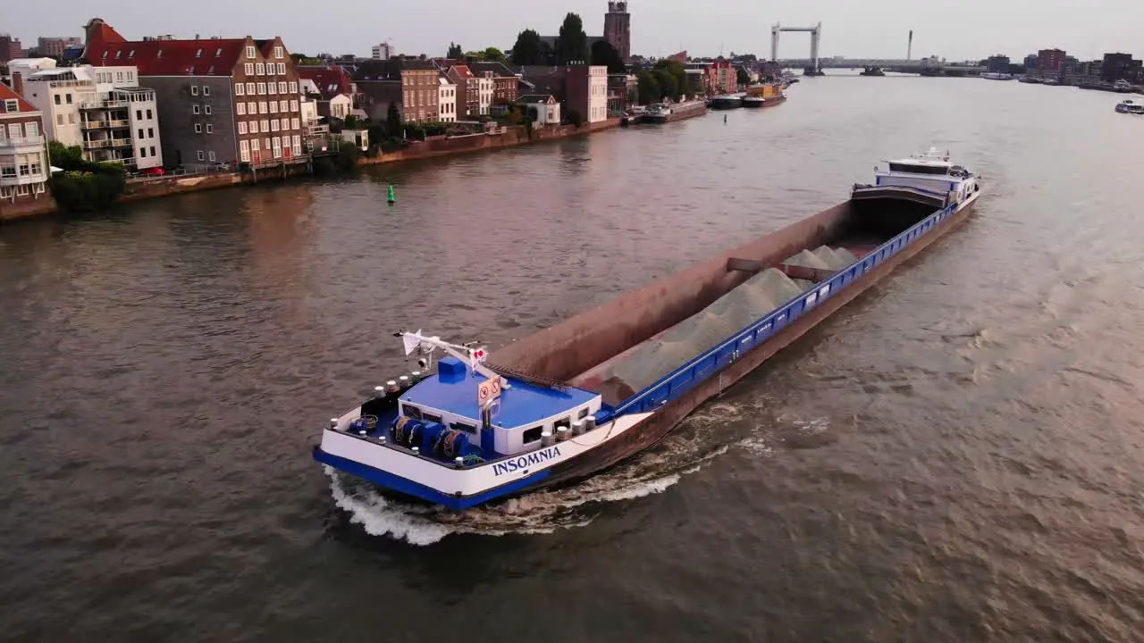 Cargo ship carrying sand through dutch canal during golden hour