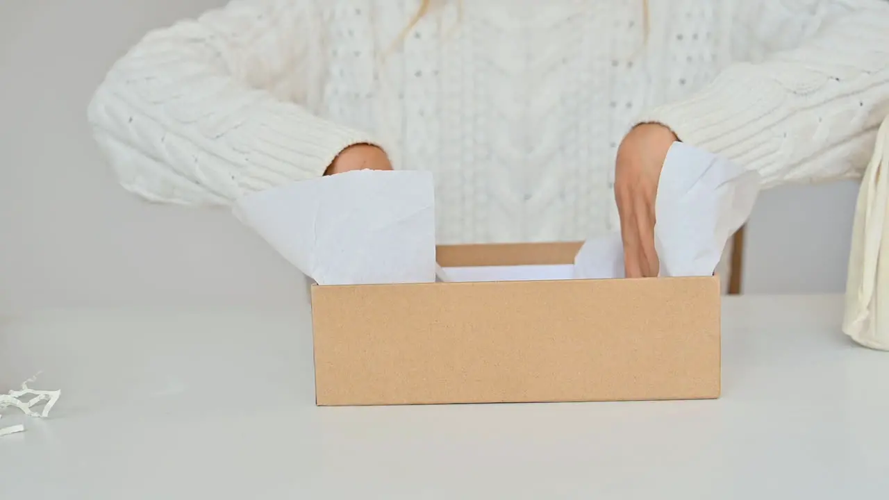 Woman Prepares Gift Box Fills It With Paper Shavings And Decorative Straw