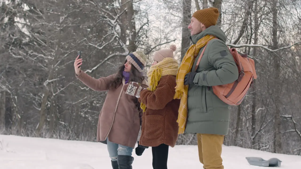 Father Mother And Daughter Taking Photos With Smartphone In A Snowy Forest