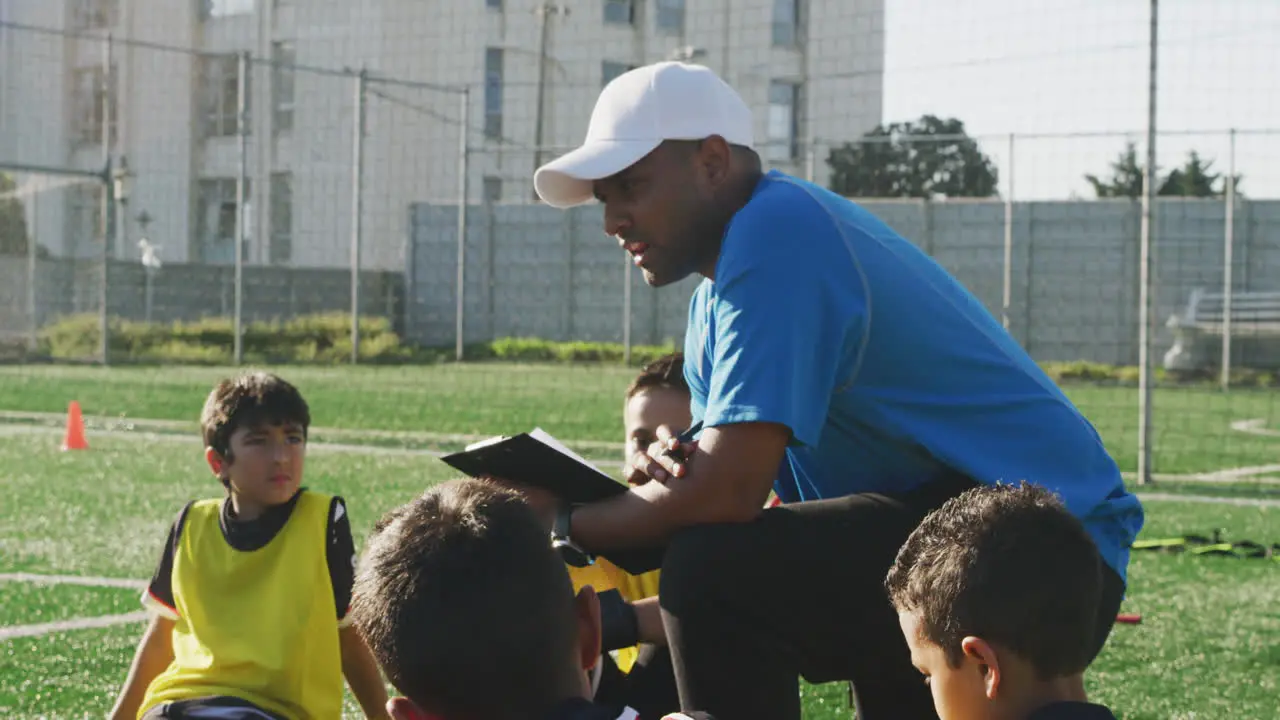 Soccer kids in cercle and listening to the coach in a sunny day