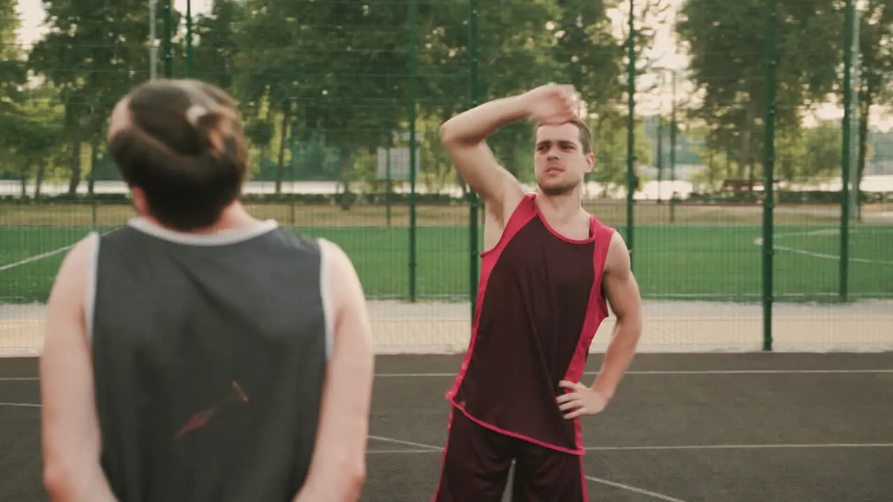 Two Male Basketball Players Stretching In An Outdoor Basketball Court Before Playing