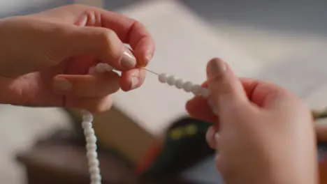 Close Up Of Muslim Woman Praying Holding Prayer Beads With Copy Of Quran In Background