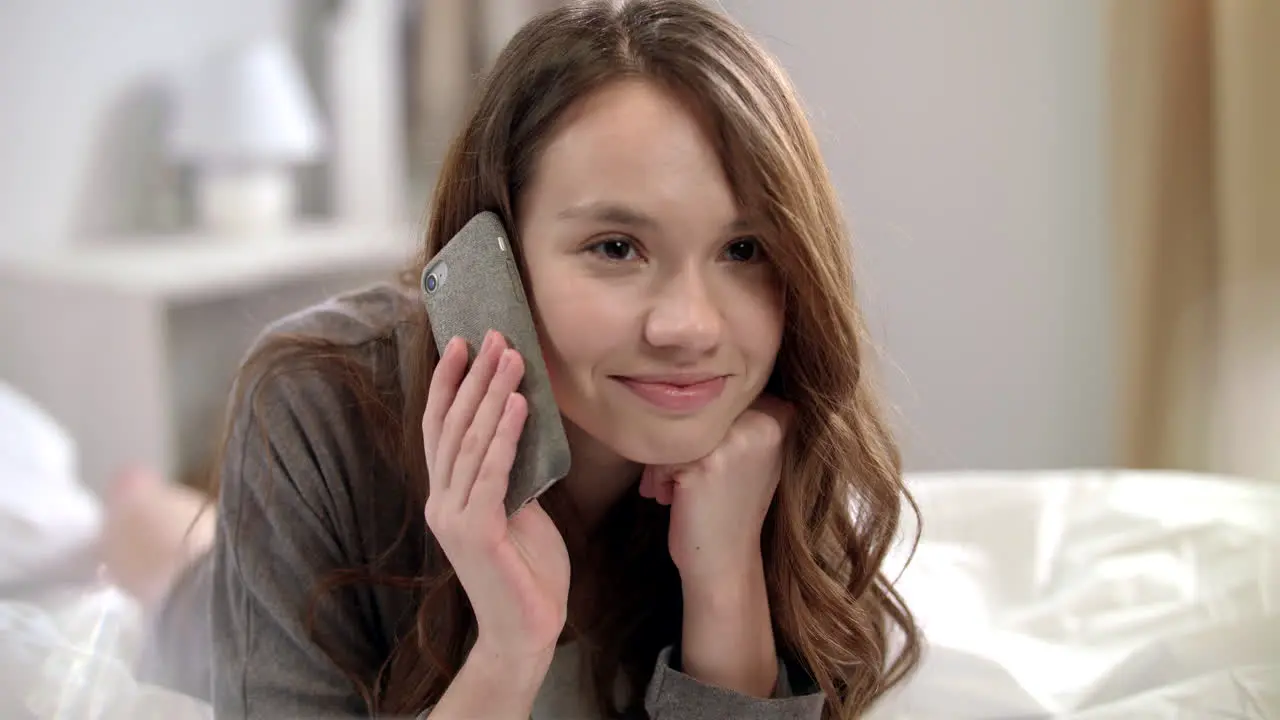 Young woman talking on mobile phone in bed Smiling woman talking on phone