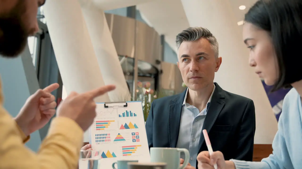 A Work Team Discusses Details Of Some Data In A Report At A Coffee Shop