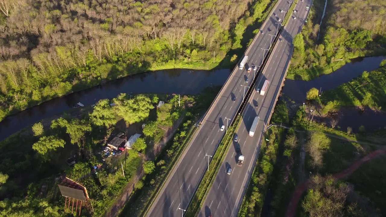 Orbit shot taken of traffic movement on Pilar Highway in Buenos Aires Argentina surrounded by plush green vegetation and going over a creek