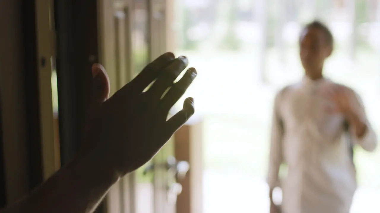 Close Up Of Hands Of Man Waving To His Son Who Standing At House Entrance In Blurred Background