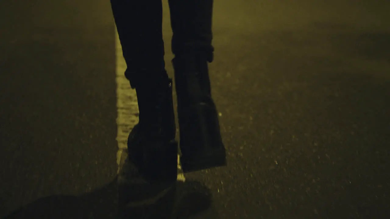 Girl walking on street alone in boots on road downtown city centre