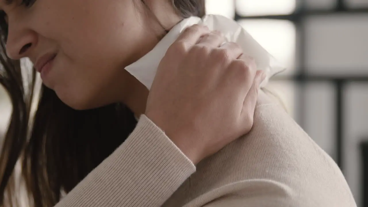 Close Up Of A Suffering Woman Trying To Relieve Neck Pain With An Ice Pack At Home