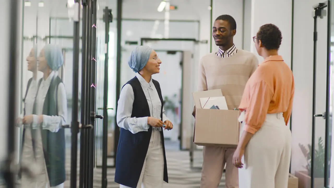 Businesswoman And Muslim Businesswoman Talk To Young Man At Office Door