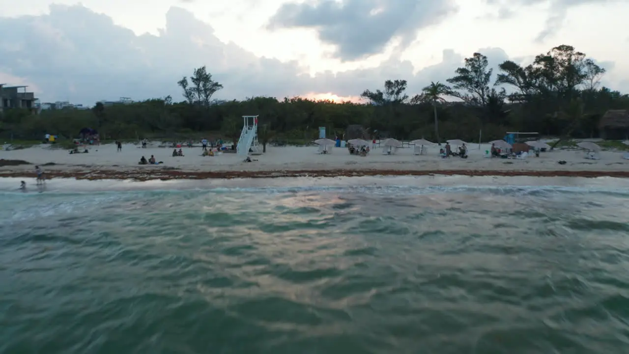 Drone flying above the water surface towards the sandy beach Rising shot revealing the city of Playa del Carmen Mexico