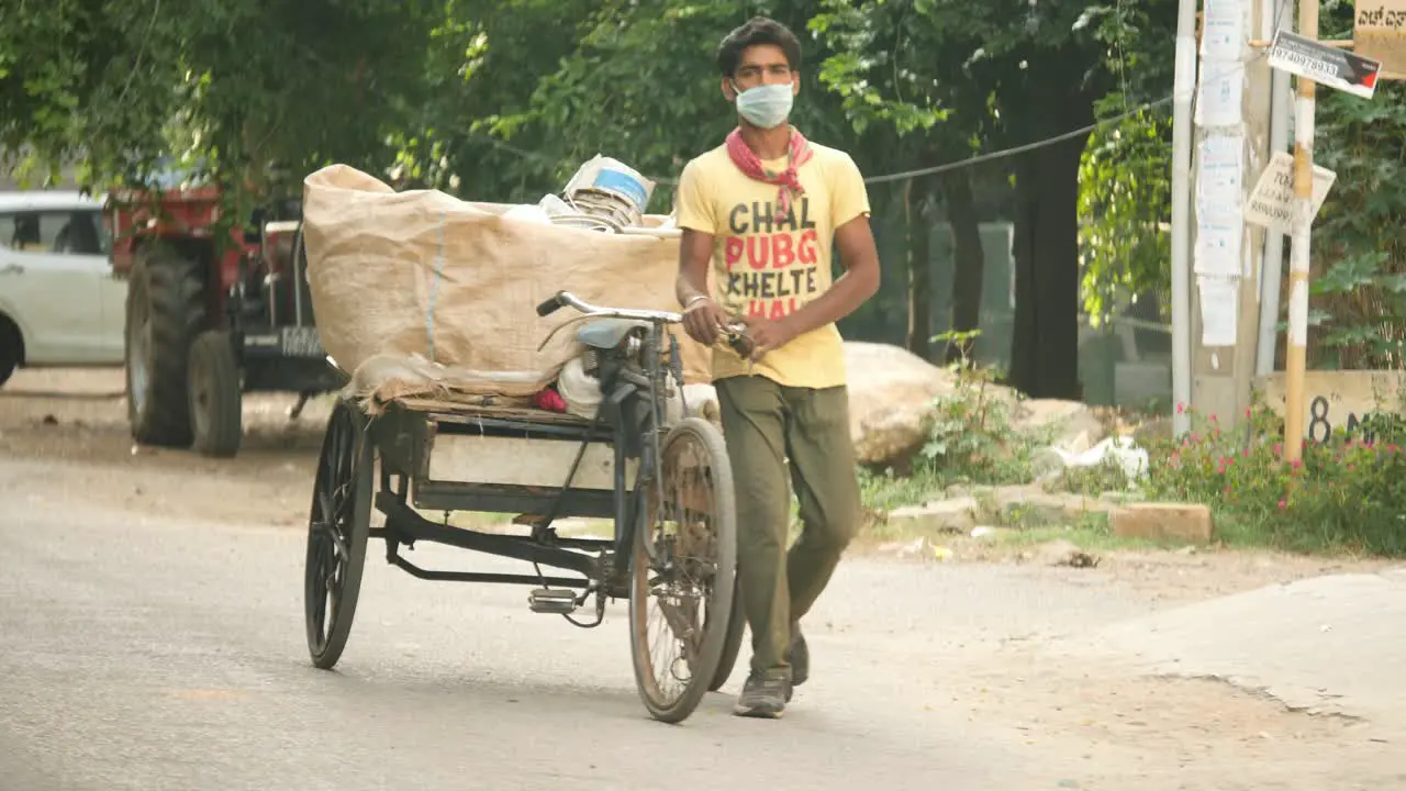 Bengaluru Karnataka India May 15 2020 A poor garbage collector wearing mask and collecting garbage on a tricycle during covid19 Pandemic 