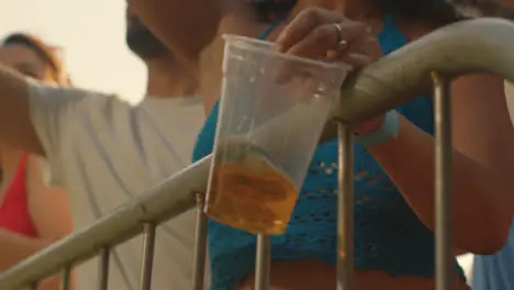 Close Up Shot of Young Festival Goers Hand Holding Beer Cup at Stage Barrier