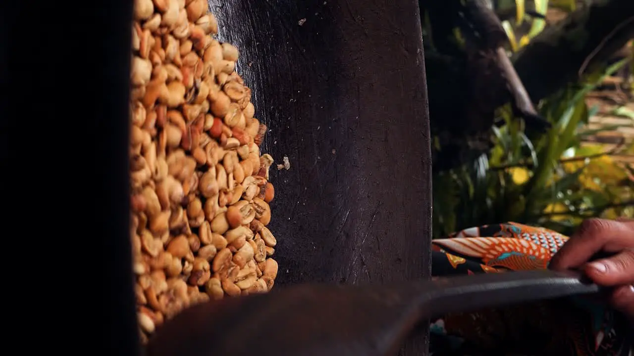 Vertical Medium slow motion shot of roasted coffee beans kopi luwak while the beans are stirred and roasted in a wok with a wooden spoon by one of the coffee plantation's employees in Bali indonesia