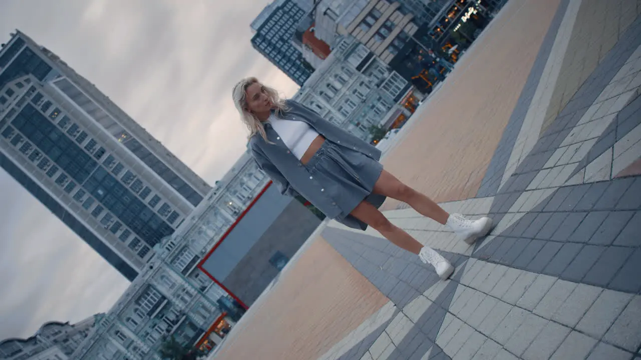 Blonde model posing city in evening on town square modern buildings