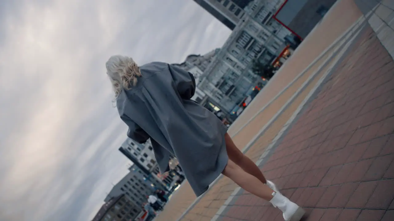 Woman walking away evening city in urban background with buildings