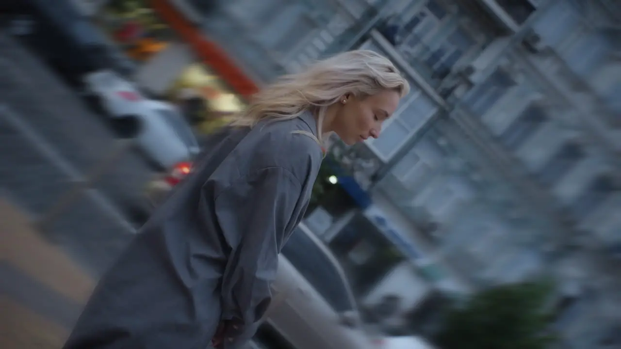 Calm woman going out in city walk at evening town road with passing cars