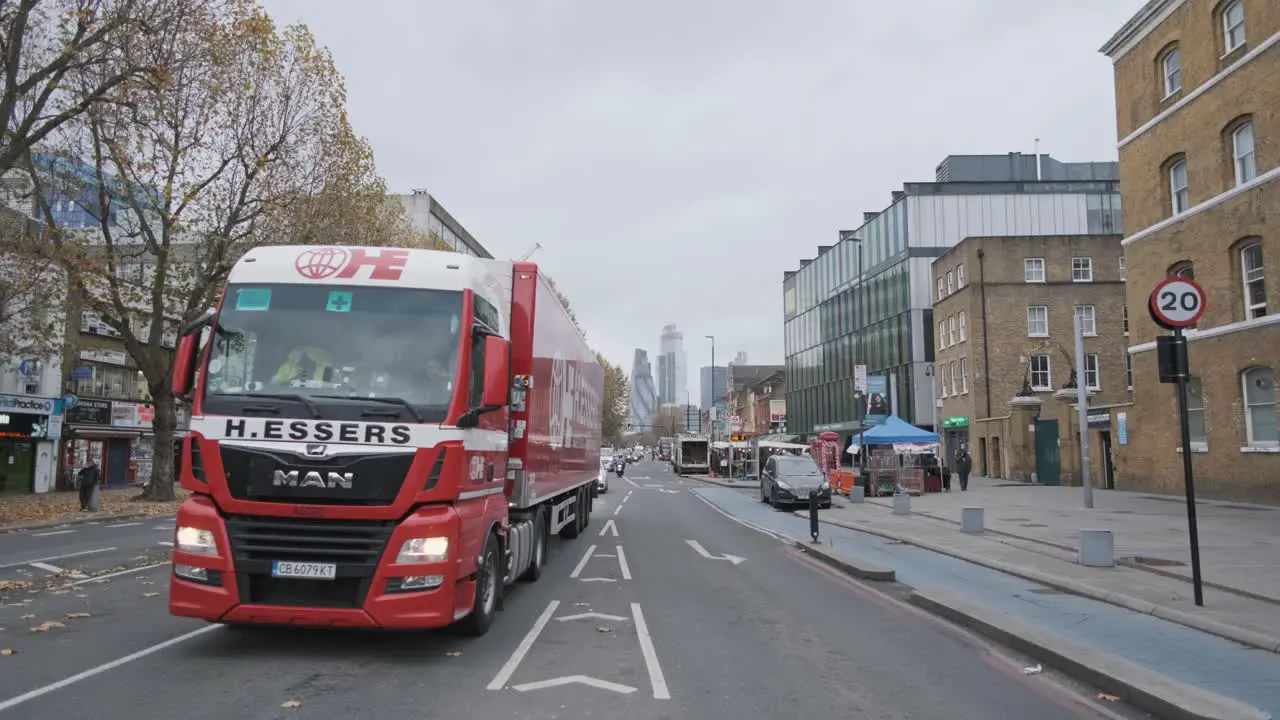 Cars driving down London Whitechapel road with city centre in background wide