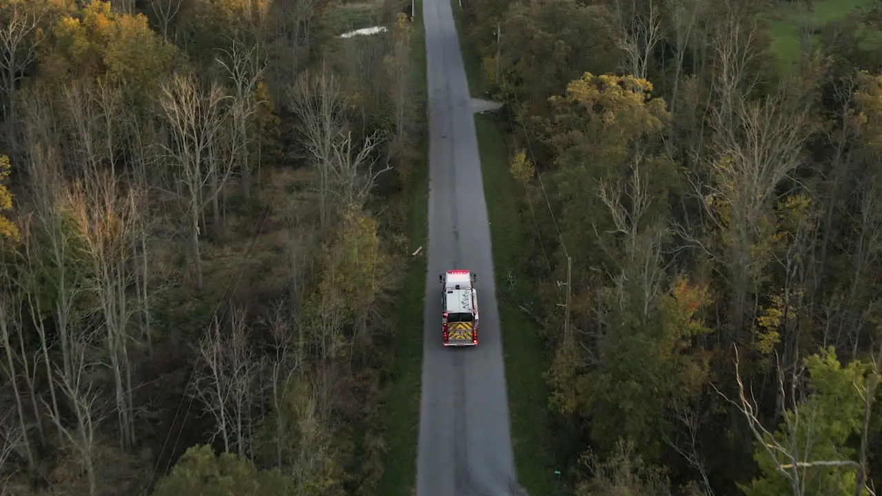 Emergency Fire Truck Vehicle Driving Fast along Straight Countryside Road with Flashing Lights Rescue First Responder Mission for Fire Fighting Alert Path Route Through Nature Lands and Trees