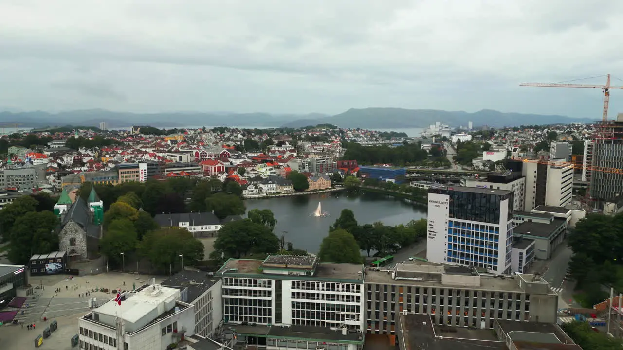 Aerial dolly toward Breiavatnet lake with fountain in Stavanger city Norway