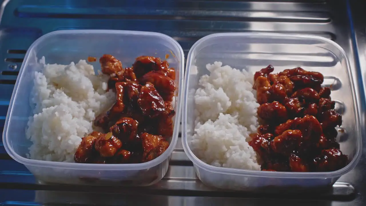 Tuppers of chicken and rice ready to eat in a kitchen close up view with zoom out