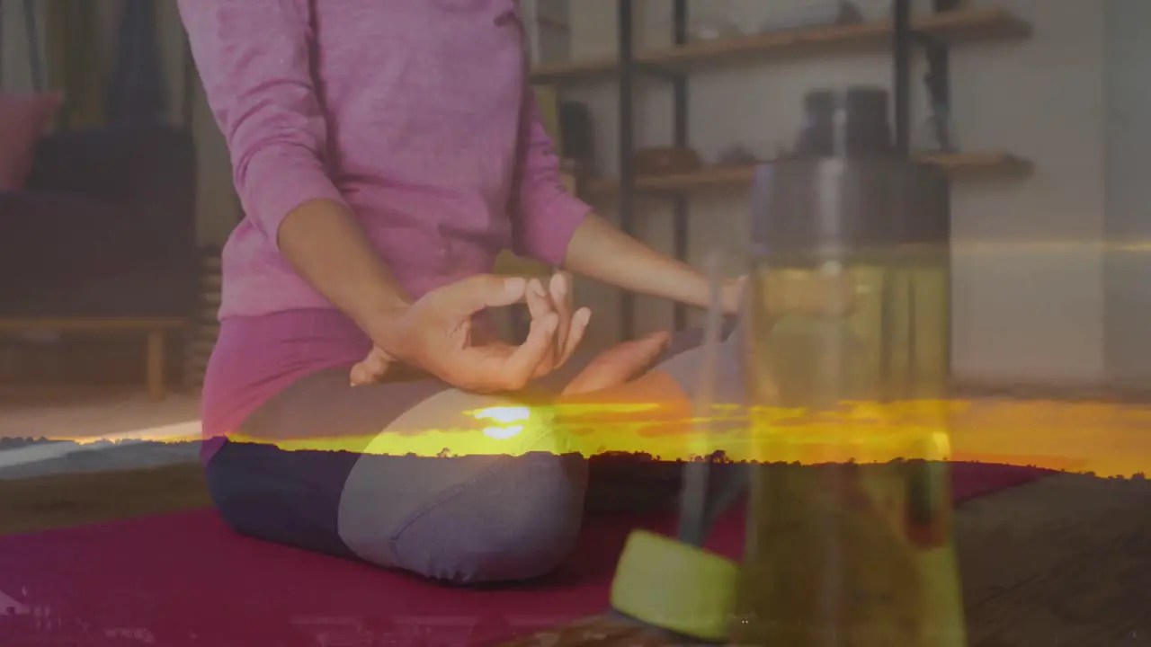 Animation of sunset landscape over woman practicing yoga exercising at home