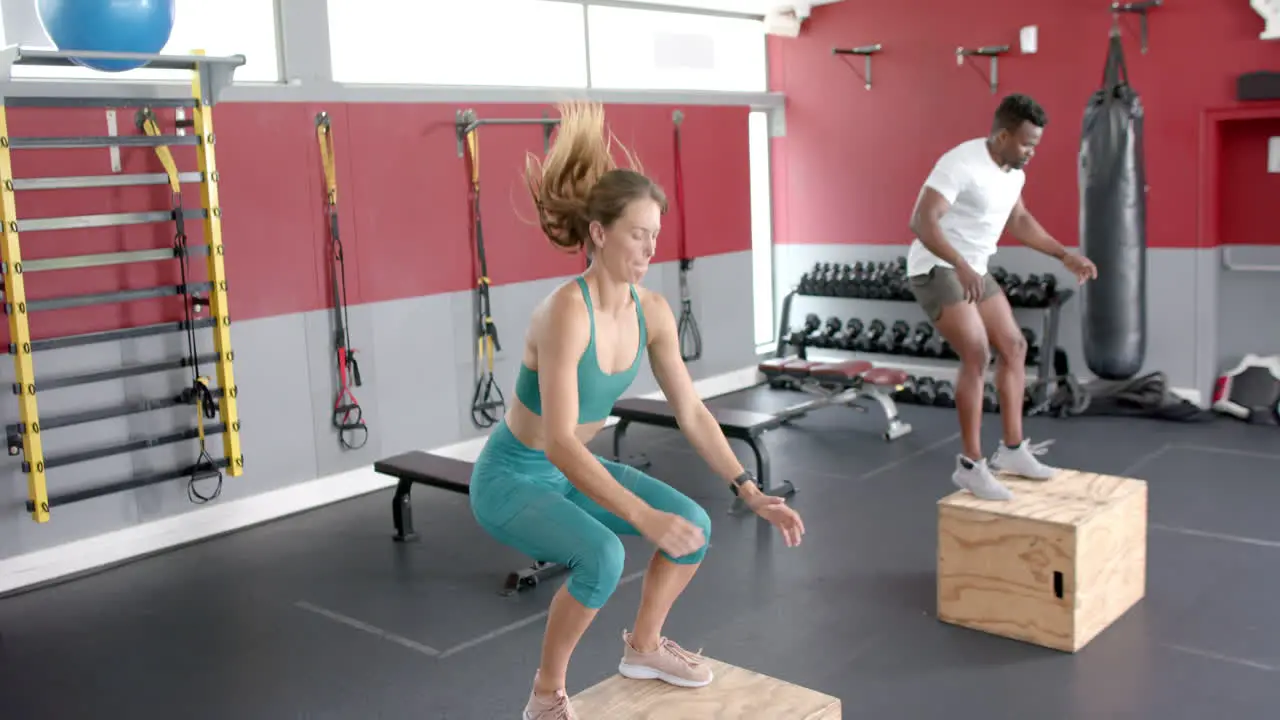 Fit young Caucasian woman doing box jumps at the gym with copy space