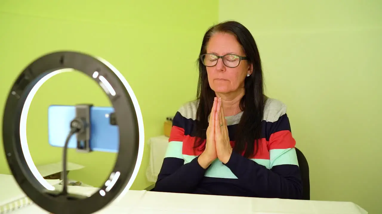 Mature Woman Meditating Sitting In Front Of Smartphone medium shot