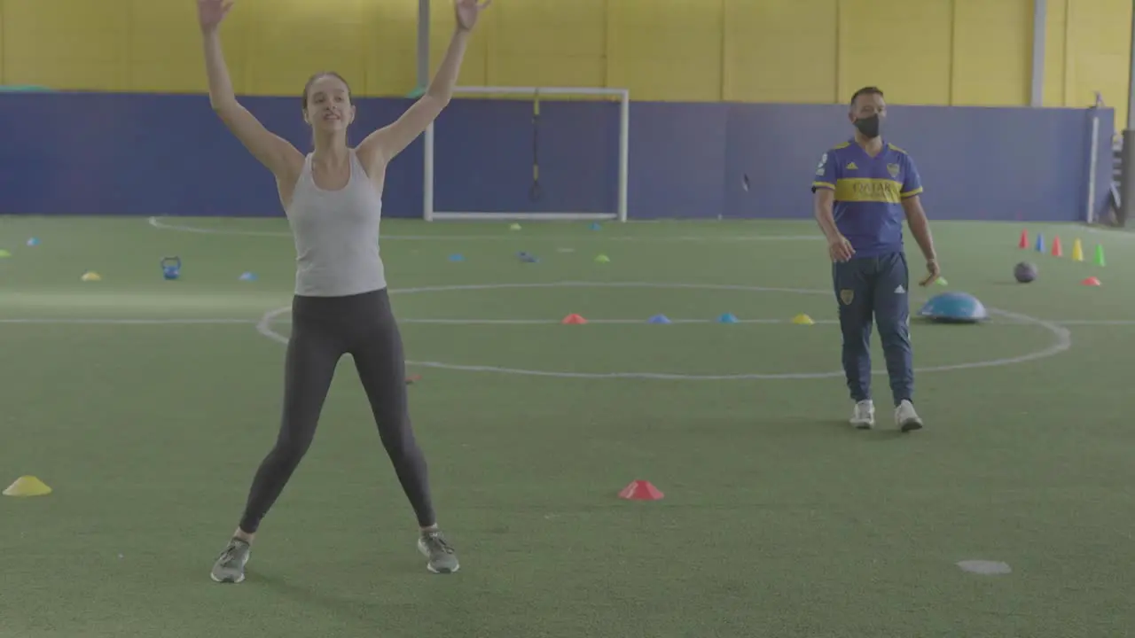 woman training on soccer field doing jumping with the trainer