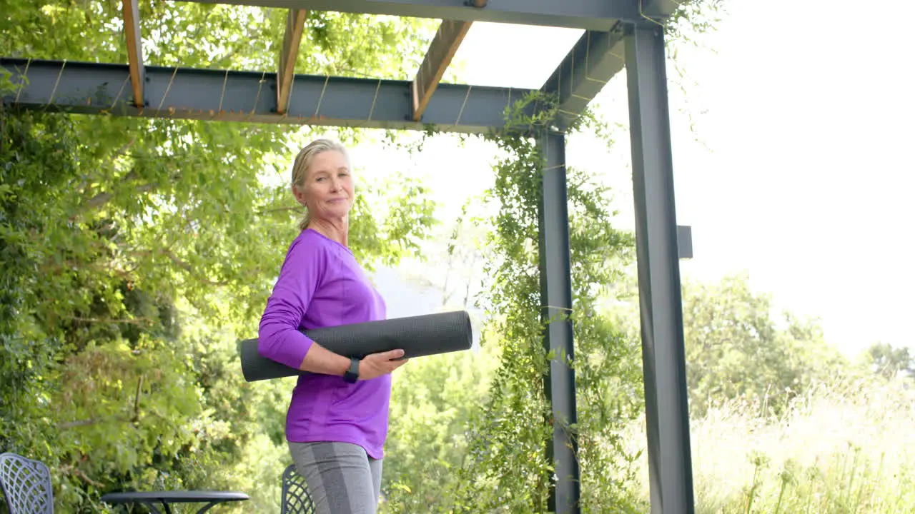 Senior Caucasian woman holds a yoga mat outdoors with copy space