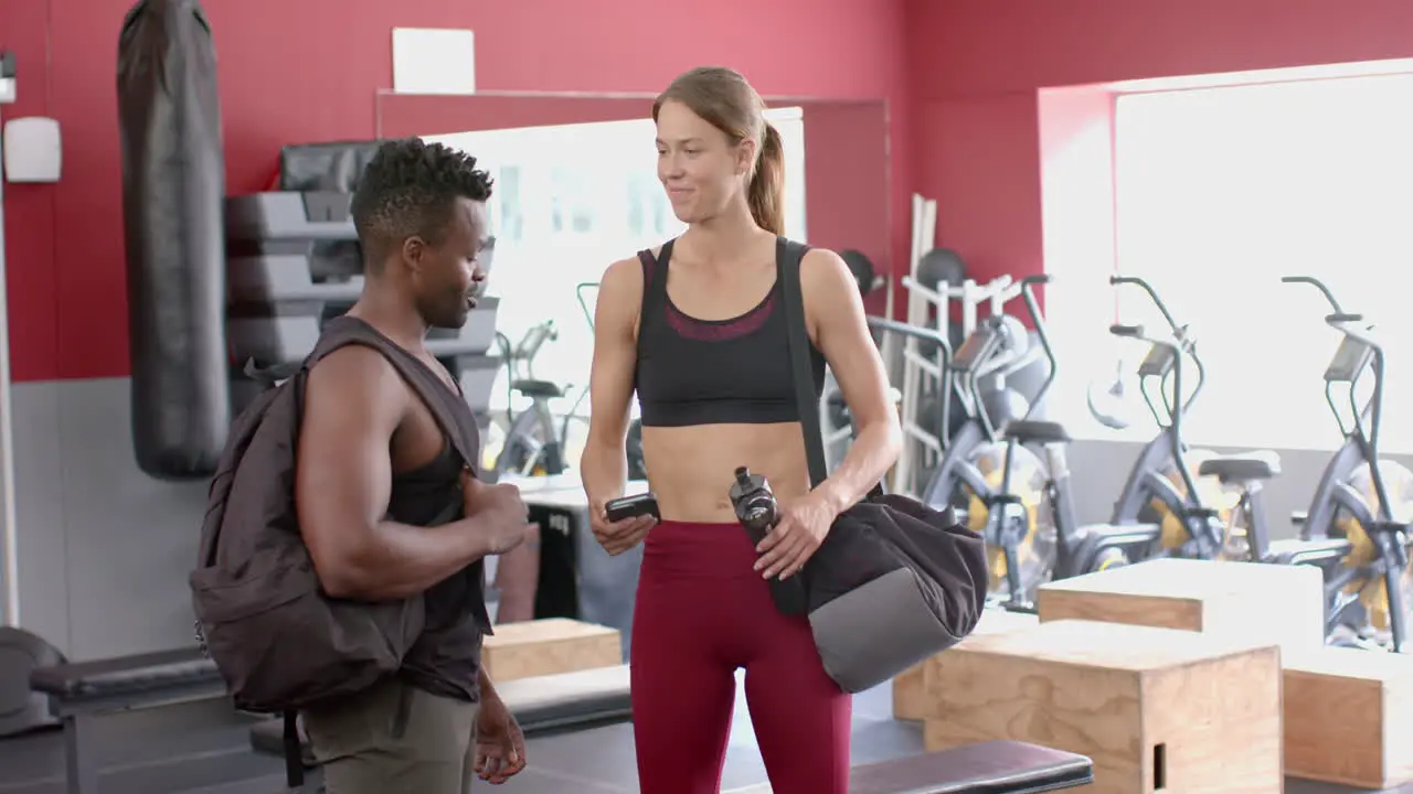 Fit African American man chats with a young Caucasian woman at the gym