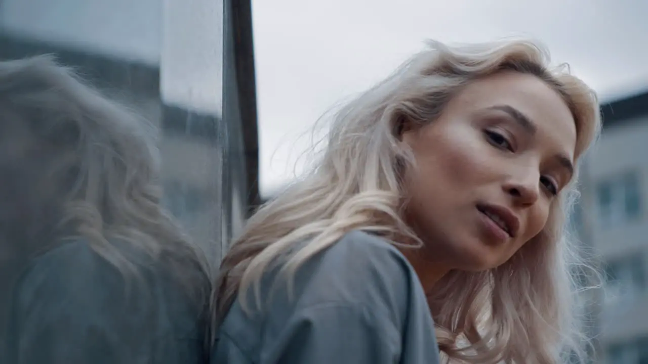 Blonde girl looking camera emotionally on urban background outdoors