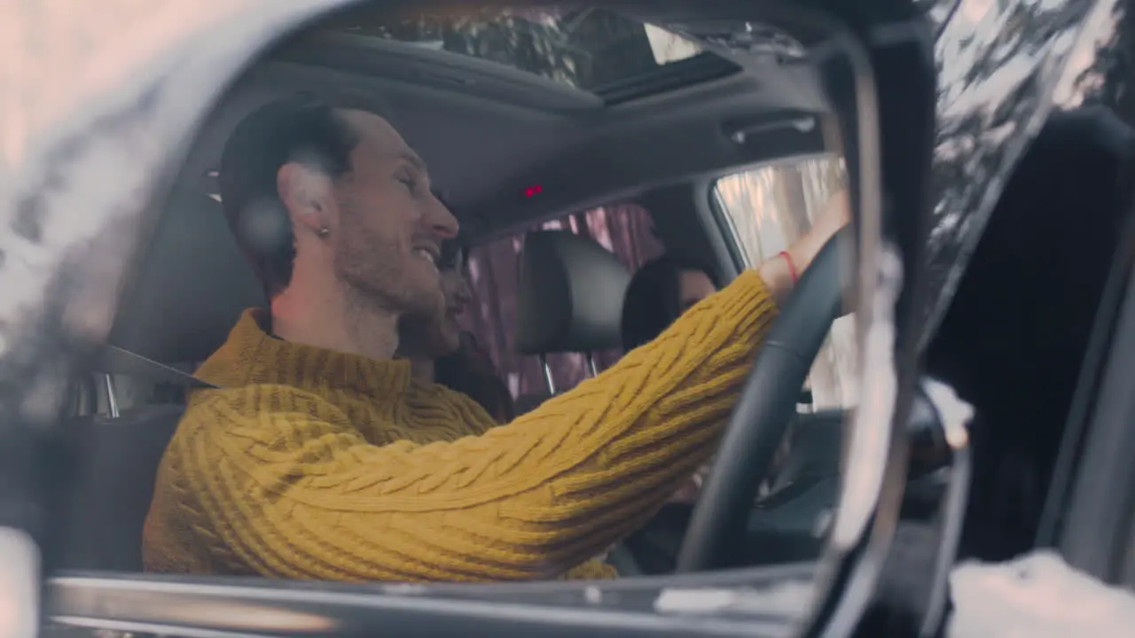 Camera Focuses On The Rearview Mirror Of A Car That Reflects A Family Dancing While Sitting Inside A Car