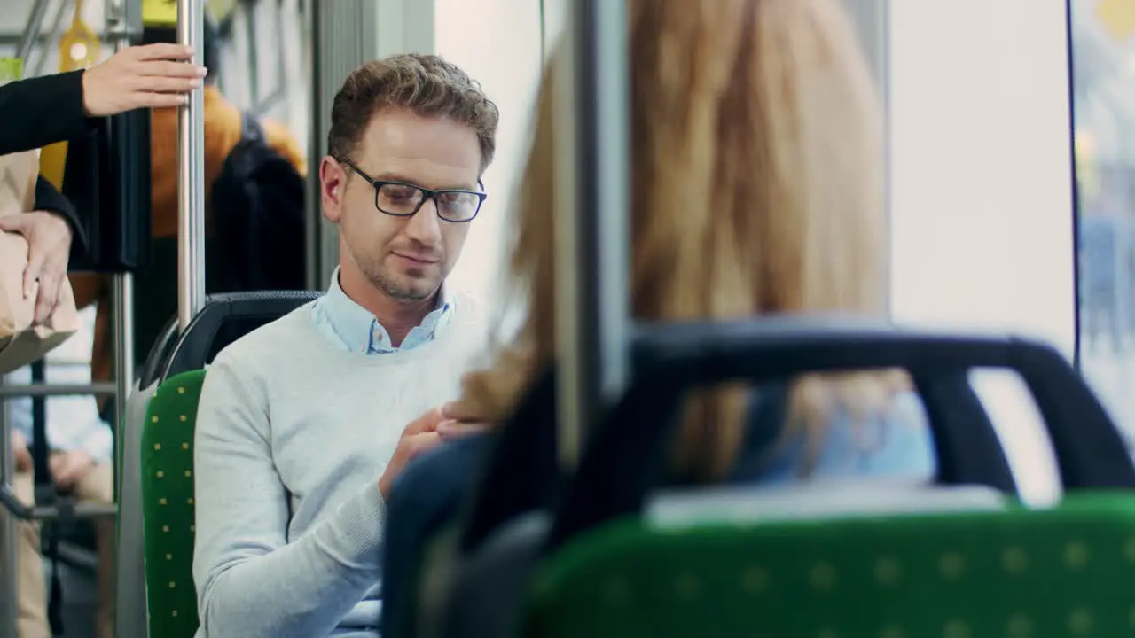 Attractive Man In Glasses Scrolling And Typing On The Phone While Going Home After Work In The Tram Or To Work In The Morning