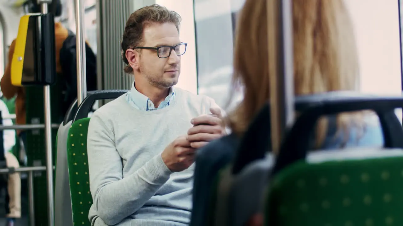 Young Good Looking Man In Glasses Tapping And Texting On The Smartphone Whle Sitting In The Tram By The Way Home Or To Work