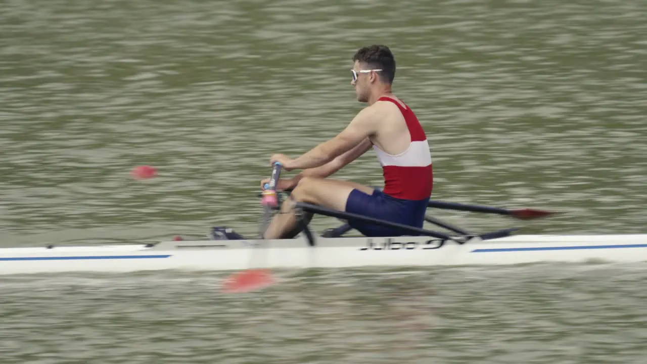 A camera follows a fast rower on a single scull during a race