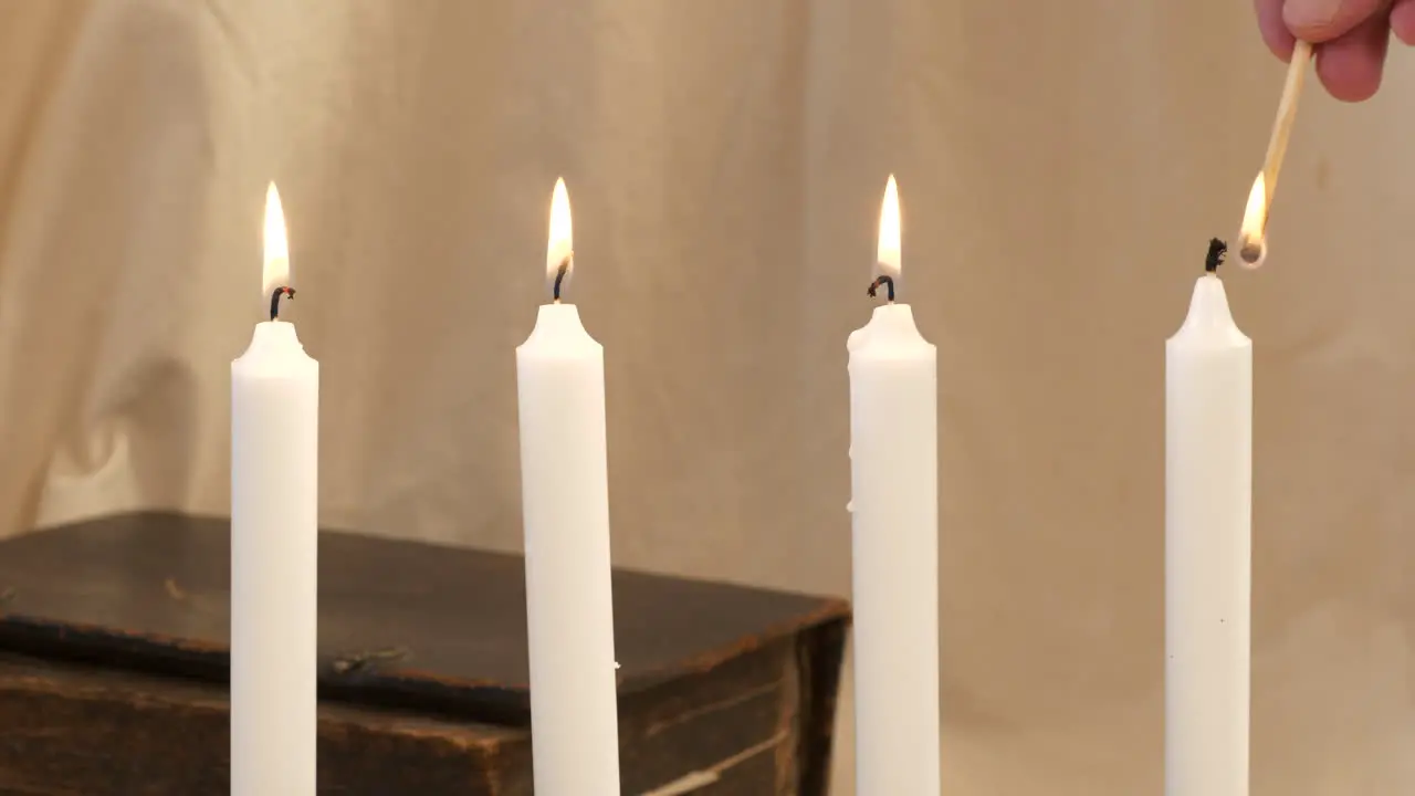 Advent candlesticks are lit by hand with match close up slider shot