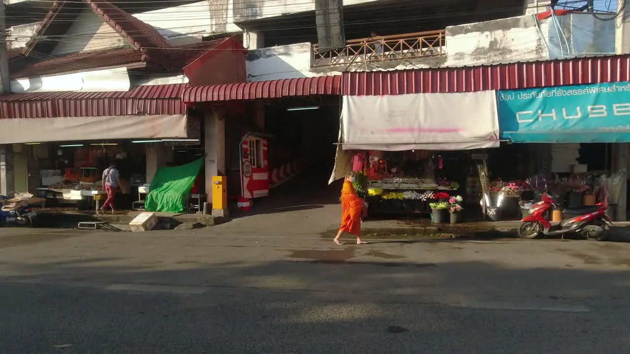 Buddhist monk in orange robe walking next to market in Chiang Mai Thailand