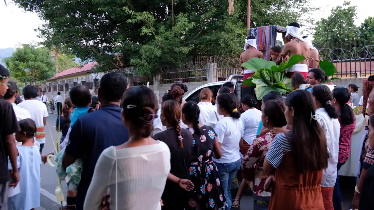 A crowd of Timorese people walking on a parade with a catholic religious statue in the capital Dili Timor Leste Southeast Asia