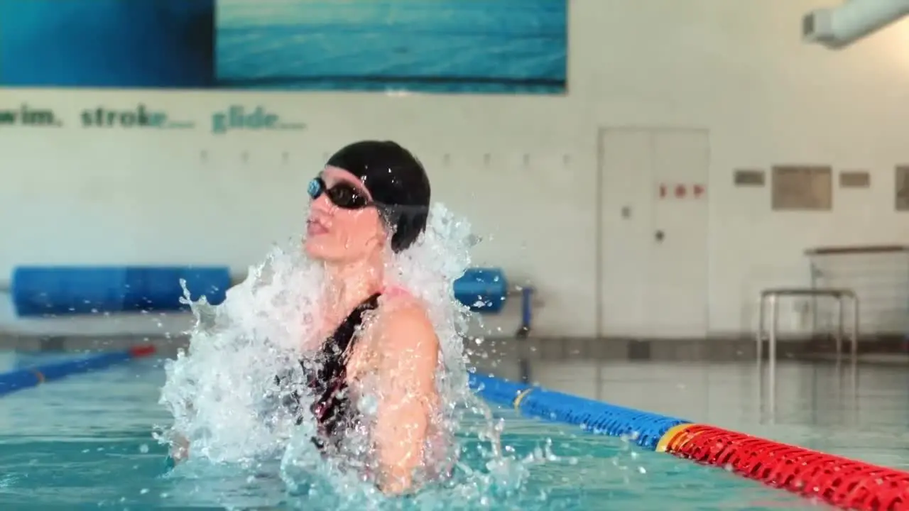 Fit woman raising arm in the pool