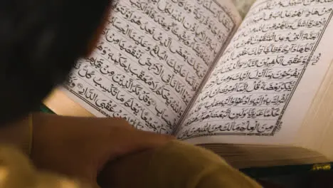 Close Up Of Muslim Man At Home Sitting On Floor And Reciting From The Quran 1