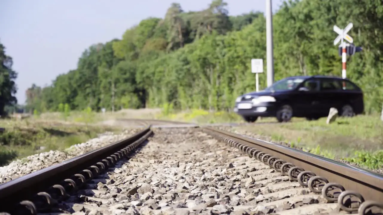 The station wagon runs through the railway crossing in countryside in 4K