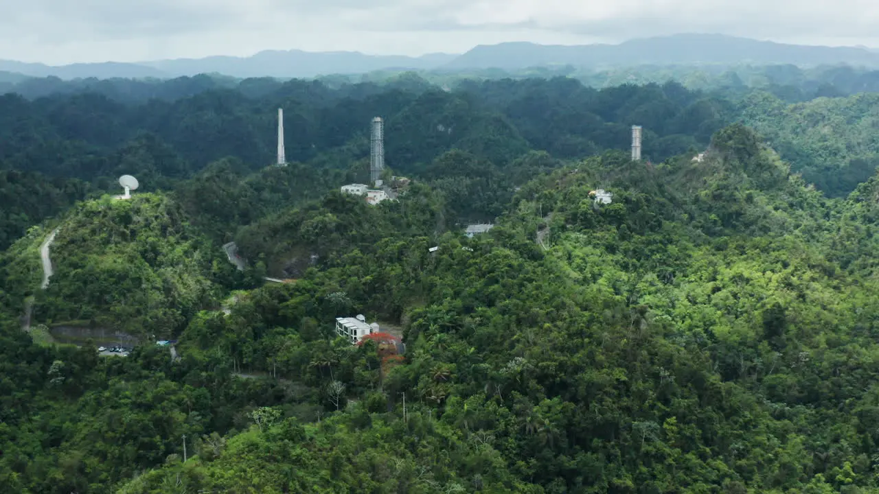 Slow zoom out of Arecibo Observatory antenna dishes and towers in Puerto Rico jungle