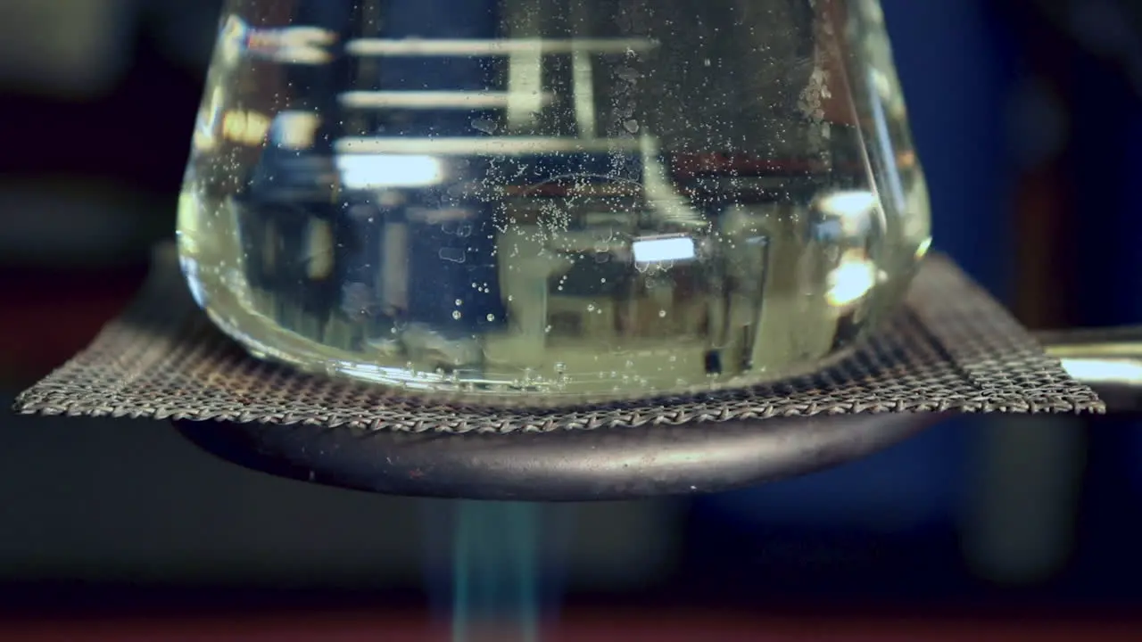 Close up of Erlenmyer Flask that is being heated by a bunsen burner less condensation on top heat waves visible in flask bubbles beginning to form